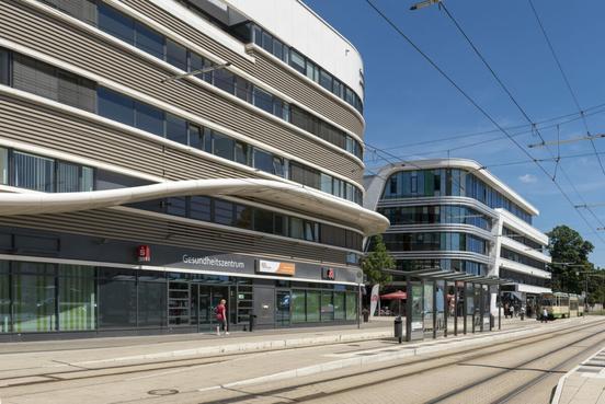 Straßenbahn-Haltestelle vor dem Gesundheitszentrum am Hauptbahnhof, moderne Gebäude und Nahverkehrsinfrastruktur